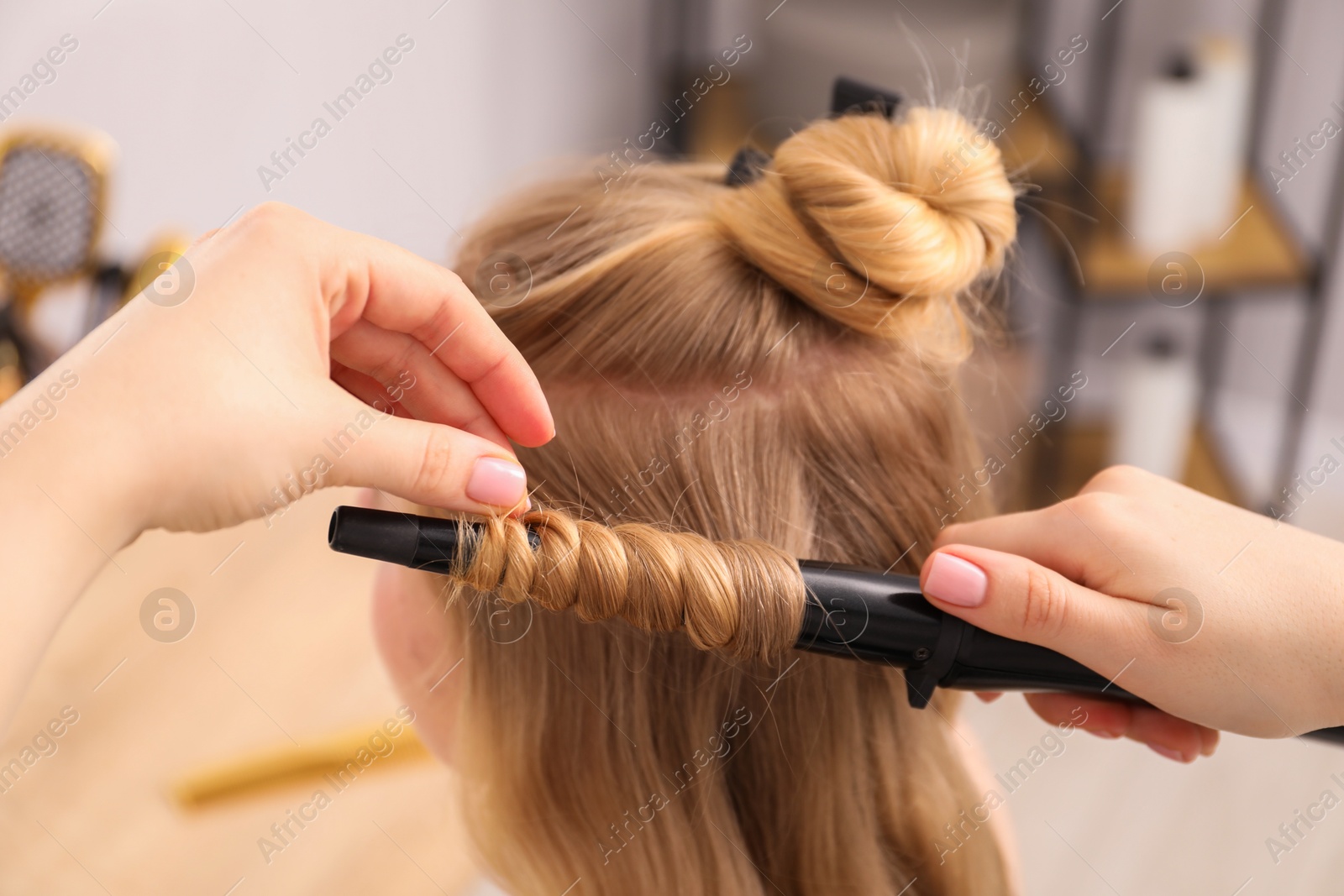 Hairdresser curling woman's hair in salon, closeup Photo of Hairdresser curling woman's hair in salon, closeup