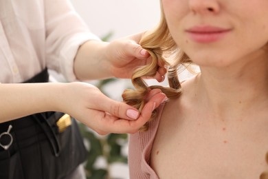 Photo of Hairdresser styling woman's hair in salon, closeup