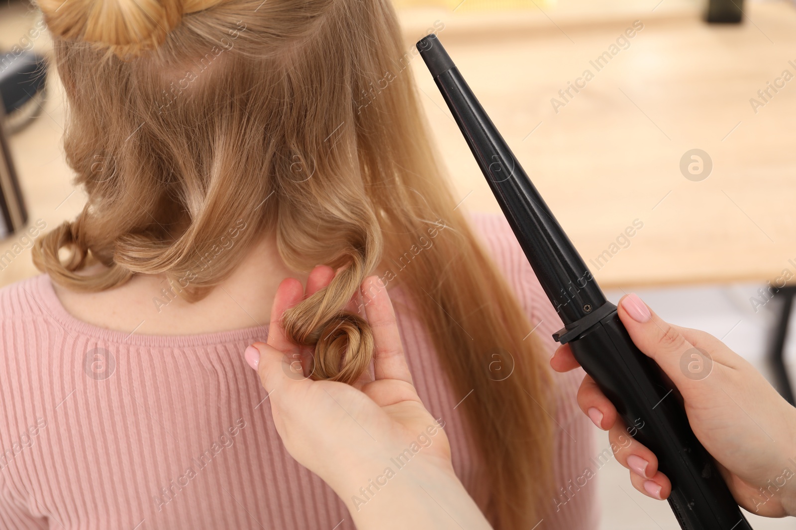 Hairdresser curling woman's hair in salon, closeup Photo of Hairdresser curling woman's hair in salon, closeup