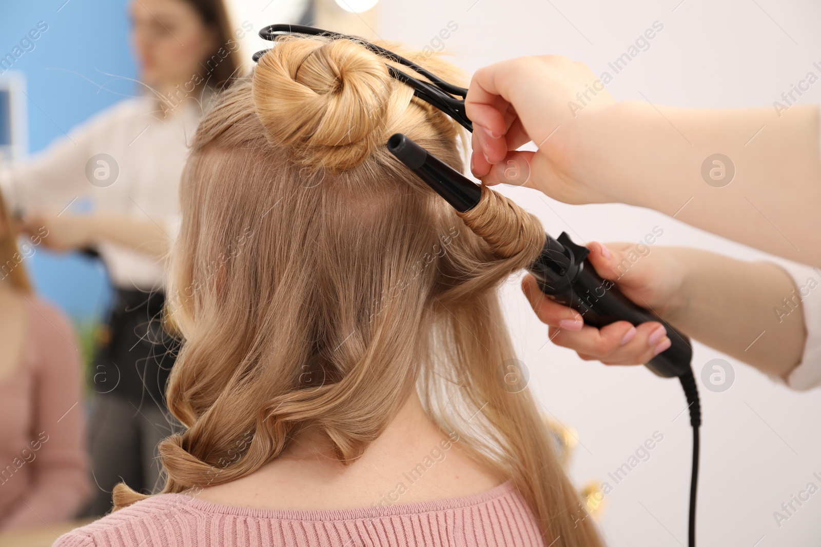 Hairdresser curling woman's hair in salon, closeup Photo of Hairdresser curling woman's hair in salon, closeup