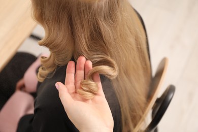 Photo of Hairdresser styling woman's hair in salon, closeup