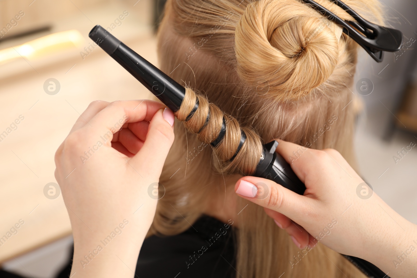 Hairdresser curling woman's hair in salon, closeup Photo of Hairdresser curling woman's hair in salon, closeup