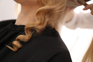 Photo of Hairdresser styling woman's hair in salon, closeup
