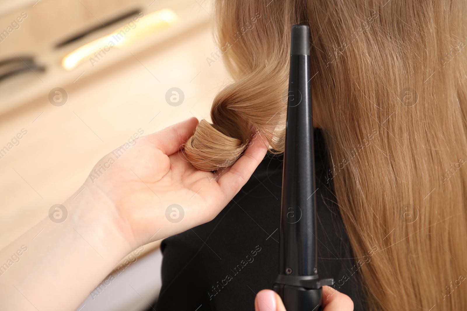 Hairdresser curling woman's hair in salon, closeup Photo of Hairdresser curling woman's hair in salon, closeup