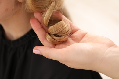 Photo of Hairdresser styling woman's hair in salon, closeup