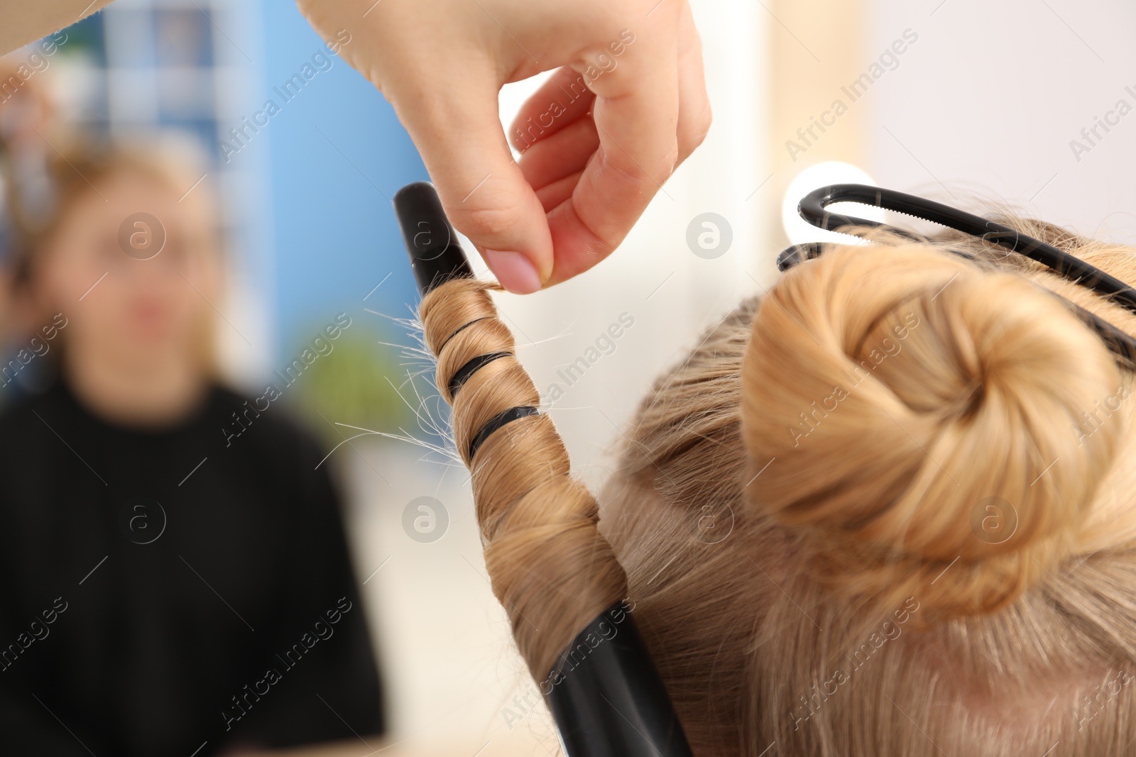Hairdresser curling woman's hair in salon, closeup Photo of Hairdresser curling woman's hair in salon, closeup