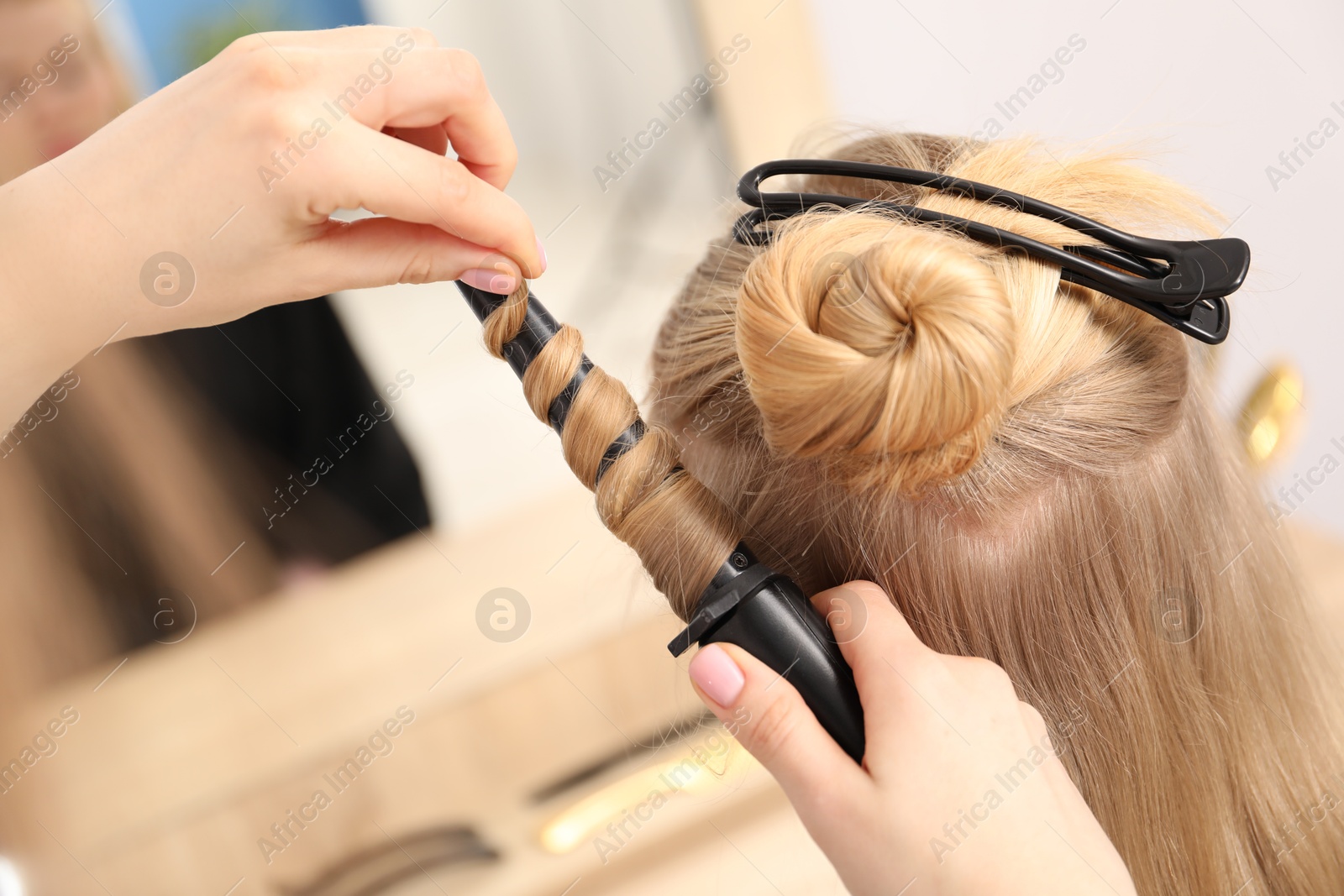 Hairdresser curling woman's hair in salon, closeup Photo of Hairdresser curling woman's hair in salon, closeup