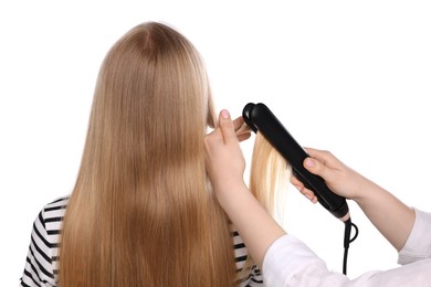 Photo of Hairdresser straightening woman's hair on white background, back view