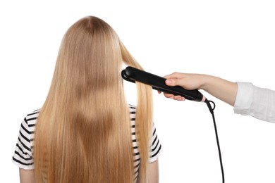 Photo of Hairdresser straightening woman's hair on white background, back view