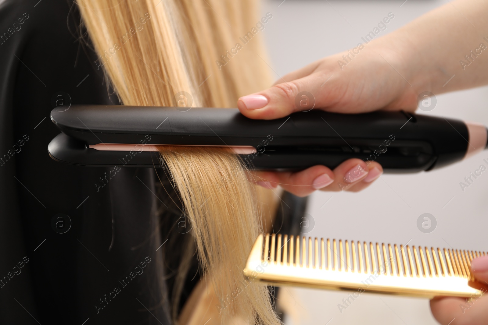 Hairdresser straightening woman's hair in salon, closeup Photo of Hairdresser straightening woman's hair in salon, closeup