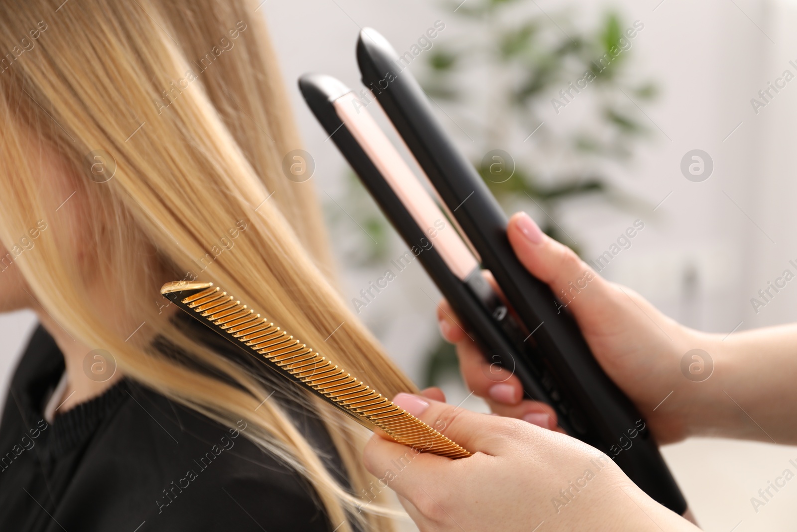 Hairdresser straightening woman's hair in salon, closeup Photo of Hairdresser straightening woman's hair in salon, closeup