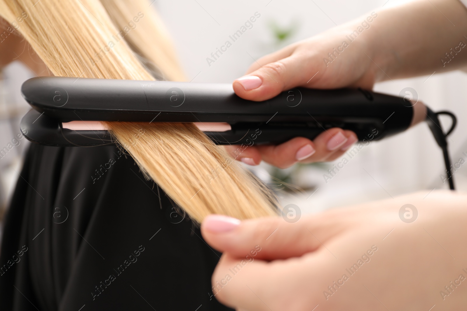 Hairdresser straightening woman's hair in salon, closeup Photo of Hairdresser straightening woman's hair in salon, closeup