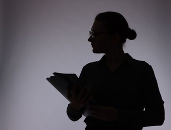Photo of Silhouette of woman with folders on grey background, space for text