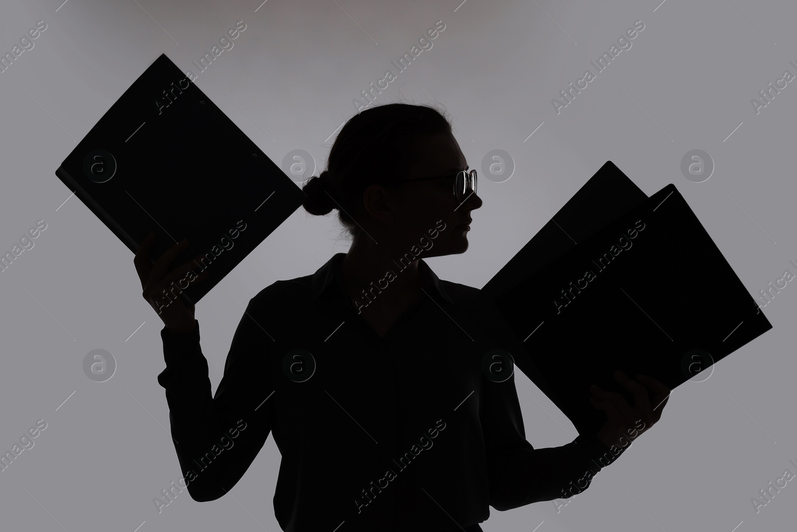 Silhouette of woman with folders on grey background Photo of Silhouette of woman with folders on grey background