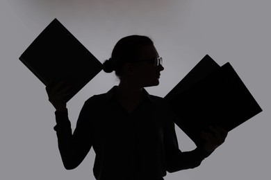 Photo of Silhouette of woman with folders on grey background