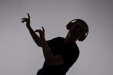 Photo of Silhouette of woman in headphones listening to music on grey background