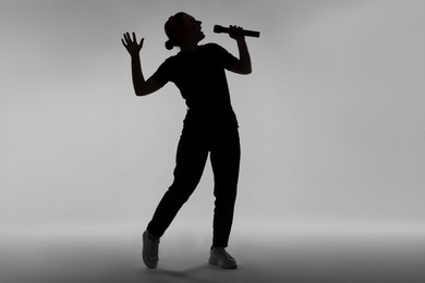 Photo of Silhouette of woman singing on grey background