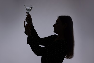 Photo of Silhouette of woman with glass of drink on grey background