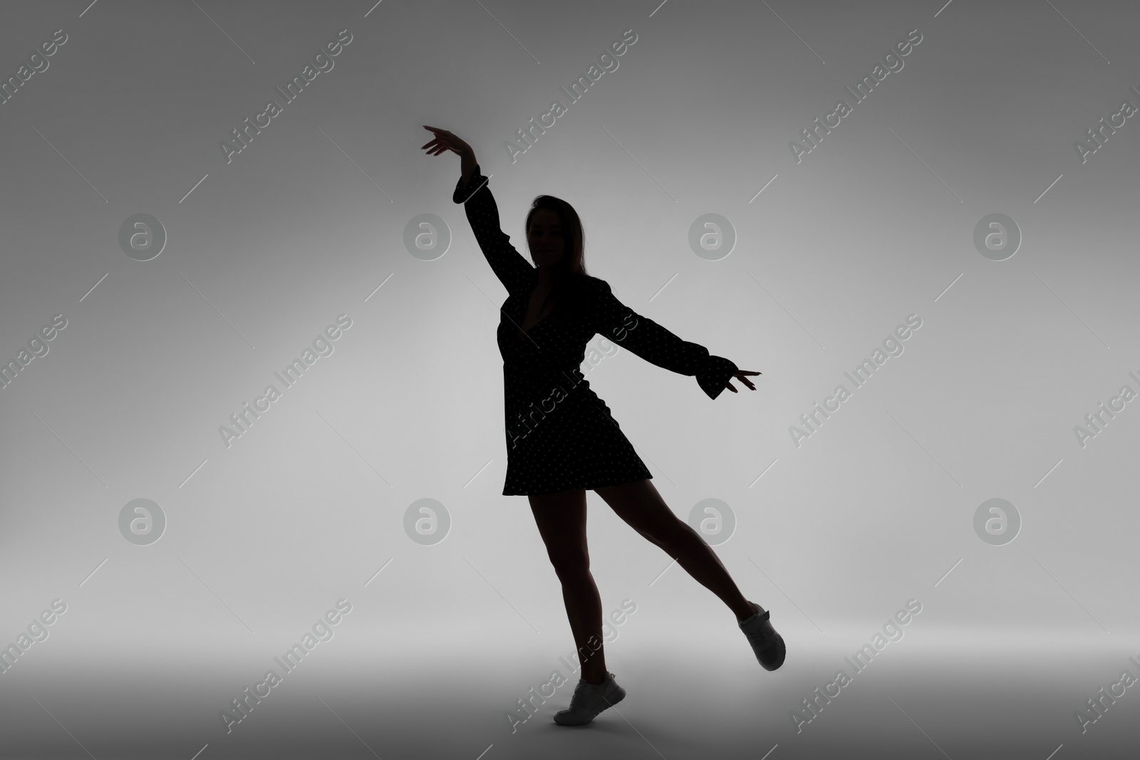 Silhouette of woman posing on grey background Photo of Silhouette of woman posing on grey background