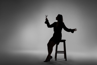 Photo of Silhouette of woman with glass of drink on grey background
