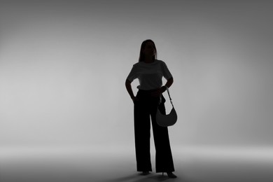 Photo of Silhouette of woman with bag on grey background