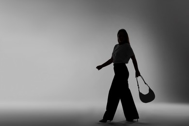 Photo of Silhouette of woman with bag on grey background