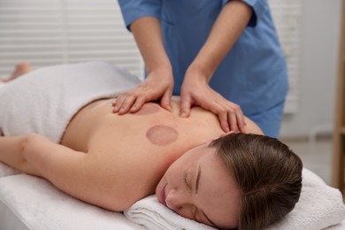 Photo of Cupping therapy. Woman receiving professional massage in spa salon
