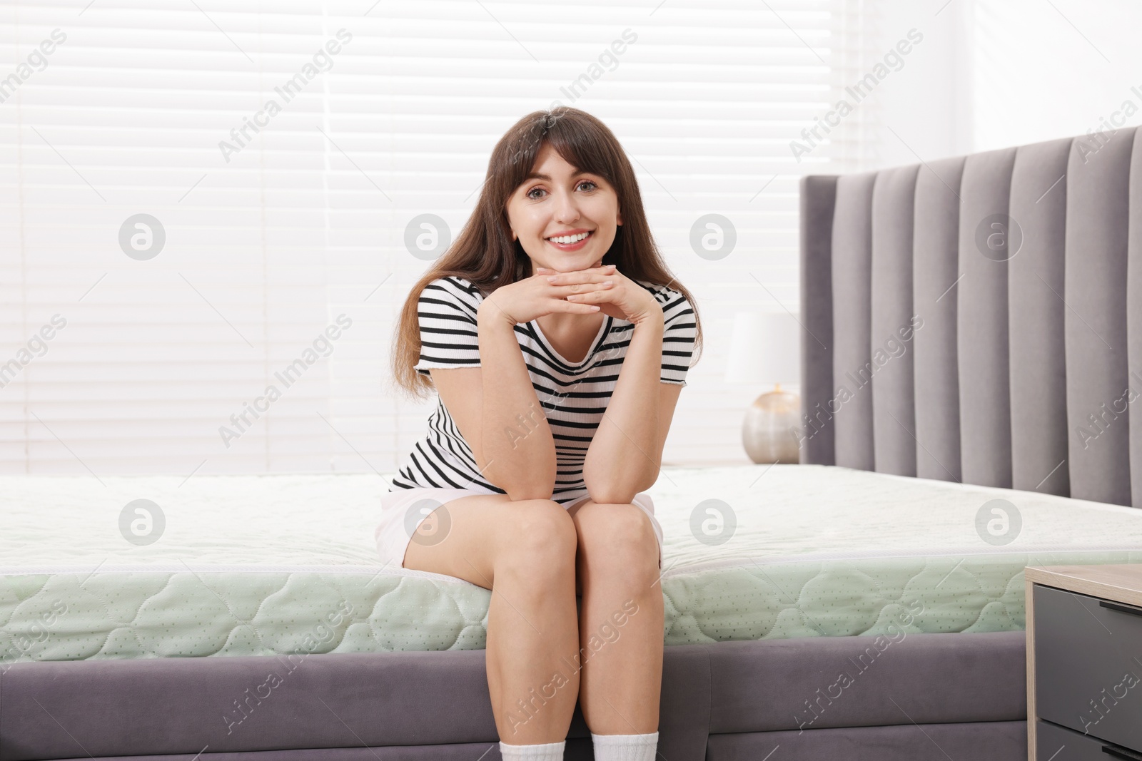 Beautiful woman sitting on soft mattress at home Photo of Beautiful woman sitting on soft mattress at home