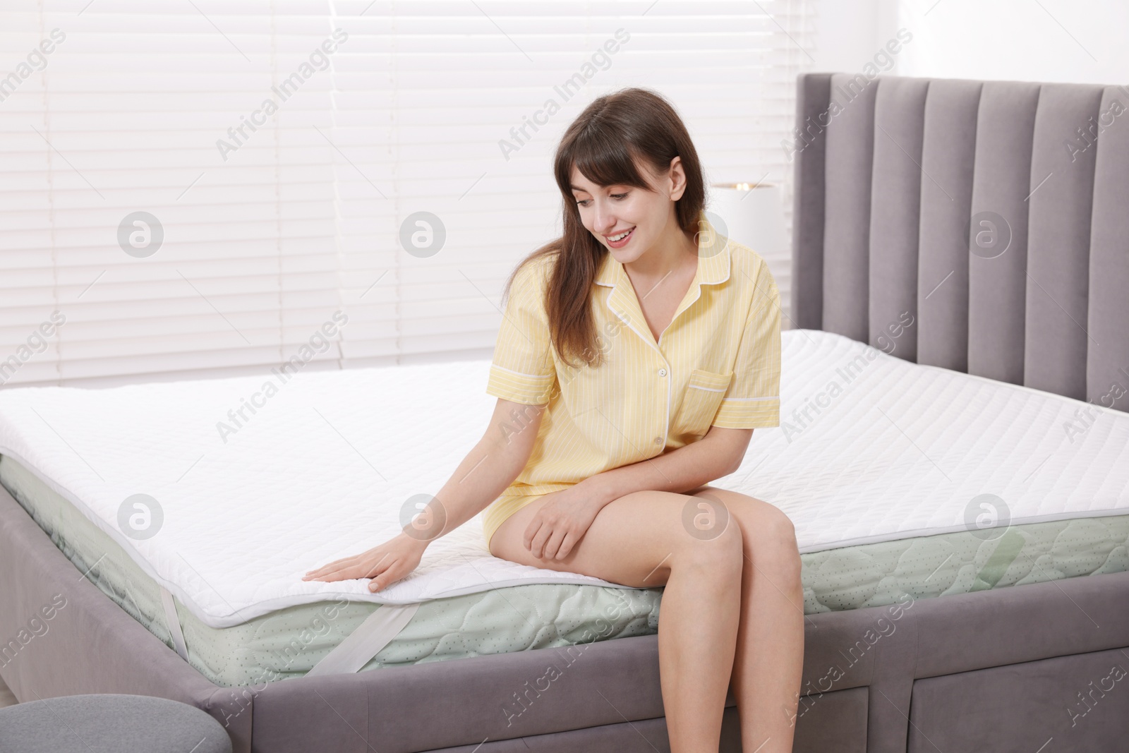 Beautiful woman sitting on soft mattress at home Photo of Beautiful woman sitting on soft mattress at home