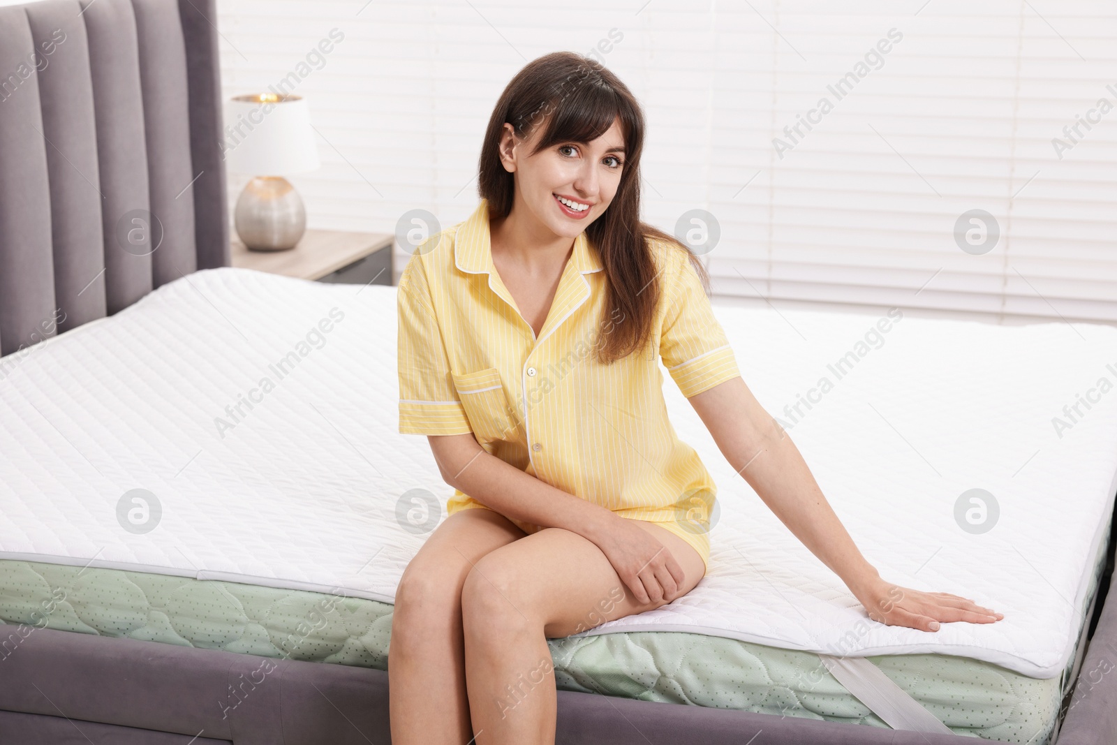 Beautiful woman sitting on soft mattress at home Photo of Beautiful woman sitting on soft mattress at home