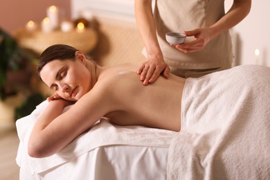 Photo of Woman receiving back massage with oil in spa salon