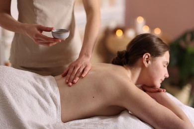 Photo of Woman receiving back massage with oil in spa salon