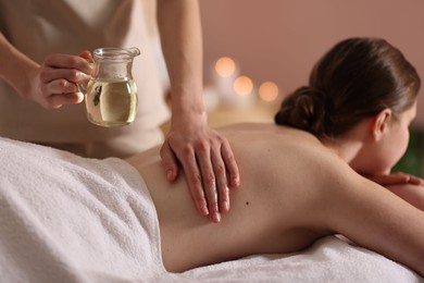 Photo of Woman receiving back massage with oil in spa salon, closeup
