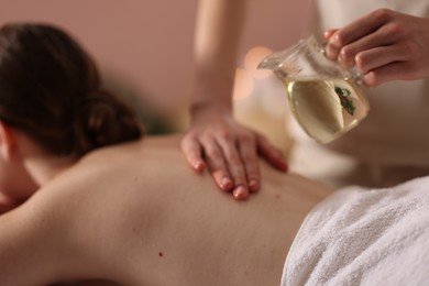 Photo of Woman receiving back massage with oil in spa salon, closeup