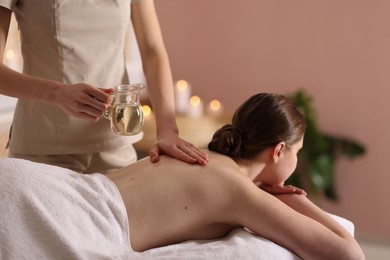 Photo of Woman receiving back massage with oil in spa salon