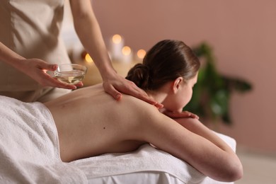 Photo of Woman receiving back massage with oil in spa salon