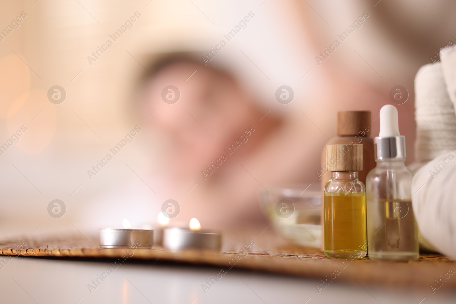 Woman receiving back massage in spa salon, focus on essential oils and burning candles Photo of Woman receiving back massage in spa salon, focus on essential oils and burning candles