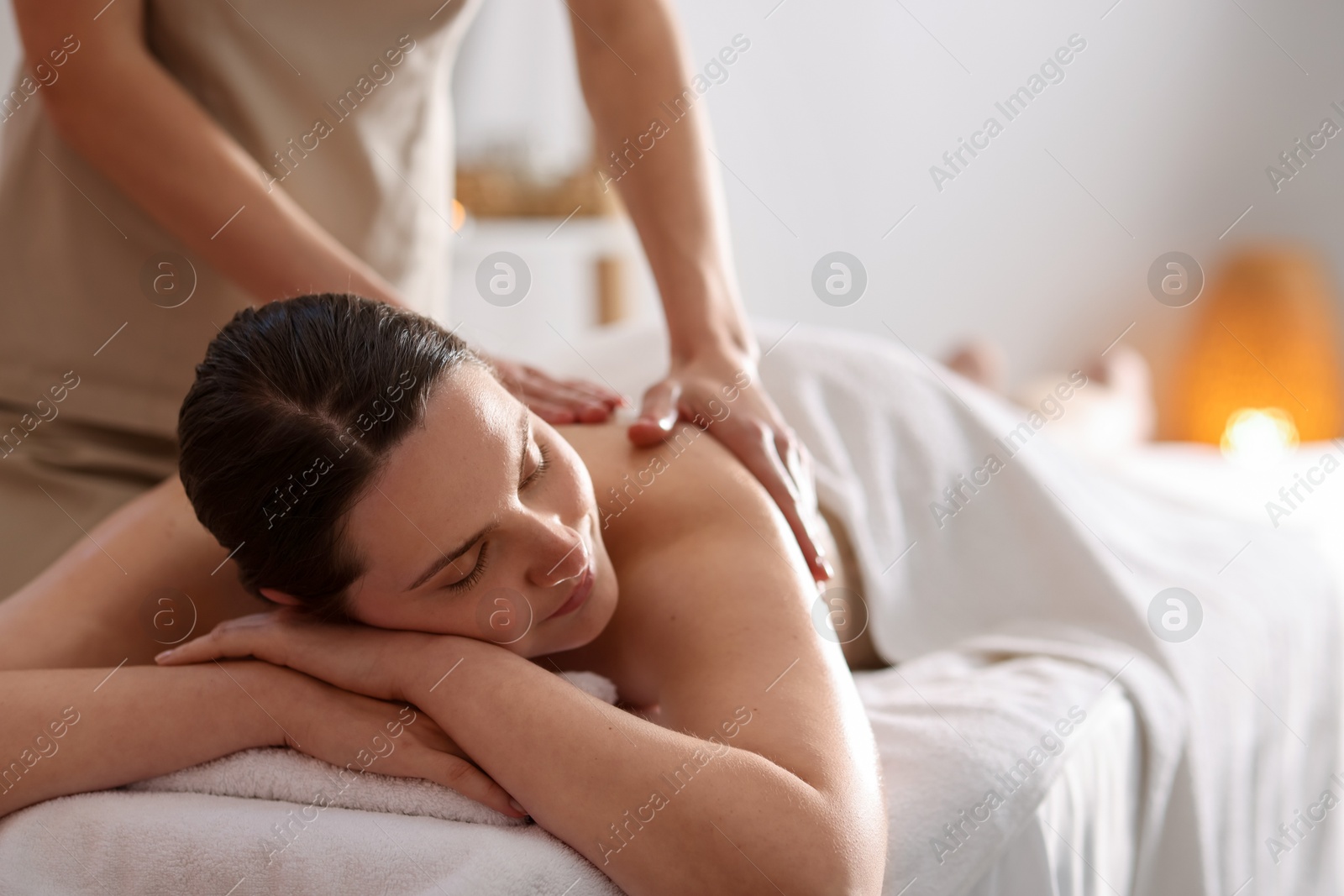 Woman receiving back massage with oil in spa salon, space for text Photo of Woman receiving back massage with oil in spa salon, space for text