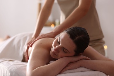 Photo of Woman receiving back massage with oil in spa salon