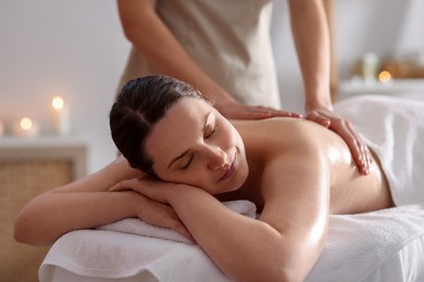 Photo of Woman receiving back massage with oil in spa salon