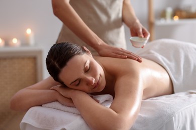 Photo of Woman receiving back massage with oil in spa salon