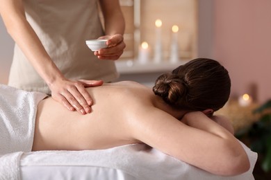 Photo of Woman receiving back massage with oil in spa salon