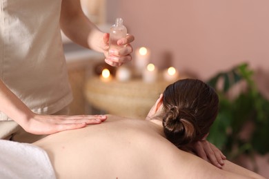 Photo of Woman receiving back massage with oil in spa salon