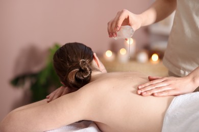 Photo of Woman receiving back massage with oil in spa salon