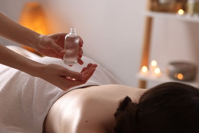 Photo of Woman receiving back massage with oil in spa salon, closeup