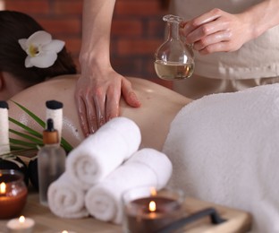 Photo of Woman receiving back massage with oil in spa salon, closeup