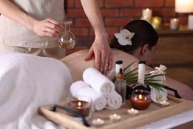 Photo of Woman receiving back massage with oil in spa salon