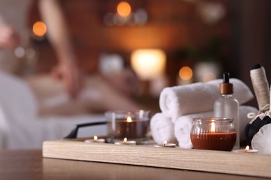 Photo of Woman receiving back massage with oil indoors, focus on different spa supplies