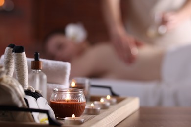 Photo of Woman receiving back massage with oil indoors, focus on different spa supplies