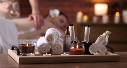 Photo of Woman receiving back massage with oil indoors, focus on different spa supplies